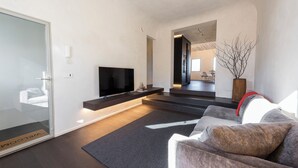 Een moderne woonkamer met een flatscreen televisie, een bank, een salontafel en een groot raam.