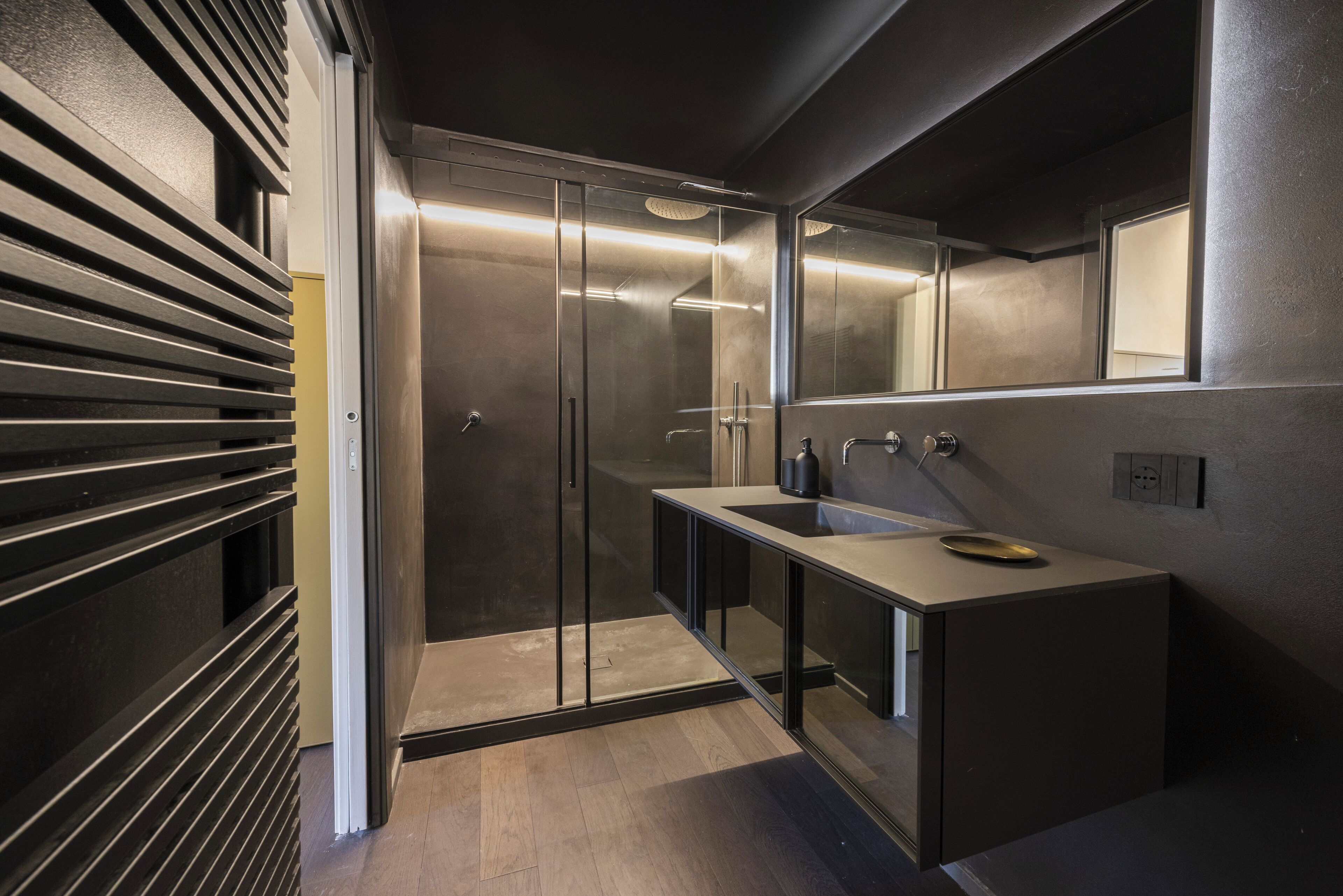 A modern bathroom with a glass shower enclosure, a vanity with a sink, and a mirror.