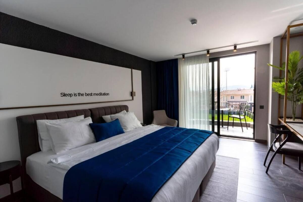 Una habitación de hotel moderna con una cama grande, un escritorio y vistas de la ciudad a través del ventanal.