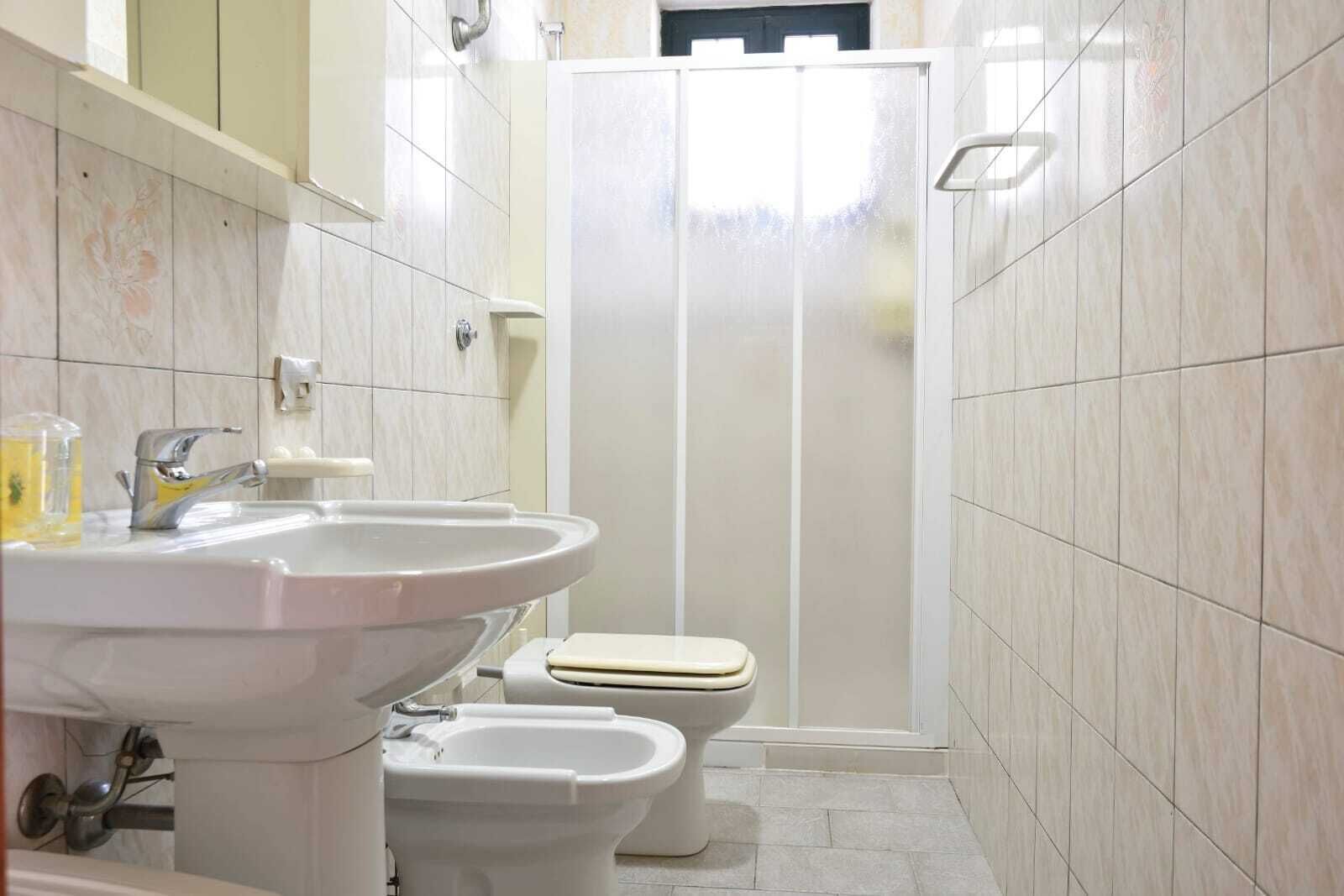 Un baño con lavamanos, inodoro, bidé y cabina de ducha.