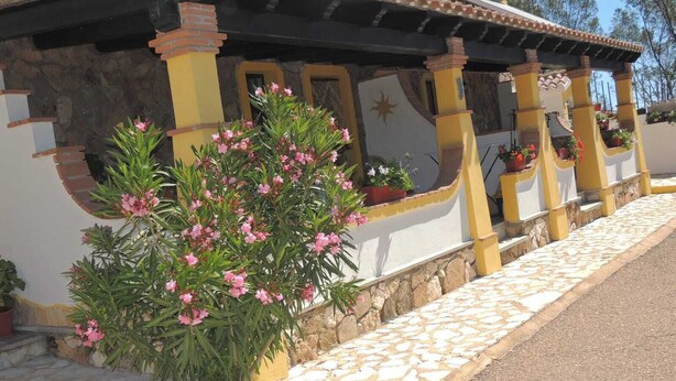 A building with a stone facade, yellow pillars, and a tiled roof.