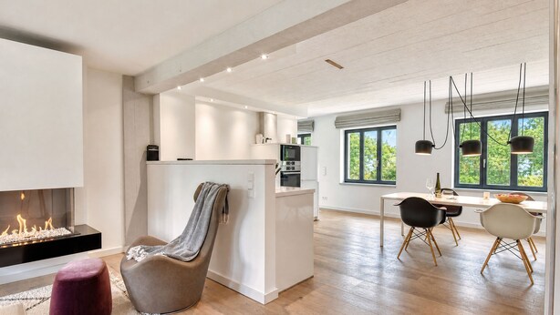 A modern kitchen with a central island, a dining area with a table and chairs, and a fireplace. - Luxury accommodation Rügenloft 4 in Prora Düne 7 with private sauna and fireplace (Prora)