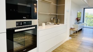 A modern kitchen with a built-in oven, microwave, and a sleek countertop. - "Purbaltic" maisonette apartment with lake view and sauna, completed in 2022 (Prora)