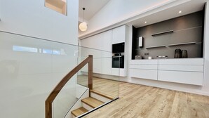 A modern kitchen with white cabinetry, a wooden staircase, and a skylight. - "Purbaltic" maisonette apartment with lake view and sauna, completed in 2022 (Prora)