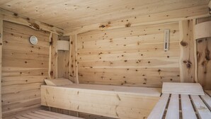 A wooden sauna with benches and a wall-mounted heater. - AlpiNest Hochgolling 2 Loft Apartment (Mariapfarr)