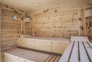 Una sauna de madera con bancos y un calentador fijado a la pared.