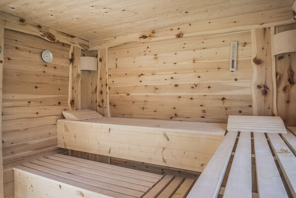 A wooden sauna with benches and a wall-mounted heater.