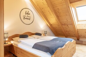 Une pièce chaleureuse avec un lit en bois, une table de chevet, une lampe et un panneau décoratif au mur.