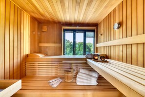 A sauna with wooden benches, a bench seat, a bench table, towels, and a bucket. - Luxury vacation apartment Meerlounge 15 in Prora Düne 7 with sea view balconies (Prora)
