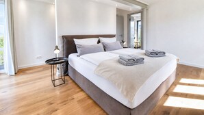 Un dormitorio moderno con una cama grande, una mesita de noche y vistas al exterior.