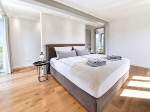 A modern bedroom with a large bed, a bedside table, and a view of the outdoors.