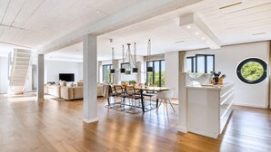 A spacious living area with a dining table, sofas, and a kitchen island.