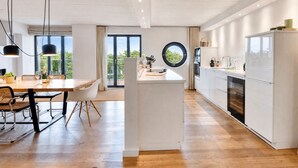 Una cocina moderna con comedor, suelo de madera y vistas amplias por las ventanas.