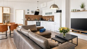 Ein modernes Wohnzimmer mit einer Couch, einem Couchtisch und einem Flachbildfernseher.