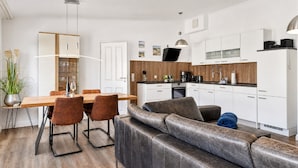 Eine moderne Küche mit weißen Schränken, einer Holz Arbeitsplatte und einem eingebauten Backofen.