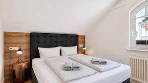 Ein Schlafzimmer mit einem großen Bett, zwei Nachttischlampen, einem Holz-Kopfteil und einem Fenster mit Blick.