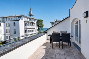 A balcony with a table and chairs, overlooking a body of water and buildings. - Beach Retreat: Luxurious ocean view at Villa Gudrun Binz. Have a wonderful family vacation (Binz)