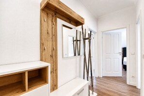 A hallway with a wooden accent wall, a white console table, and a door leading to another room.