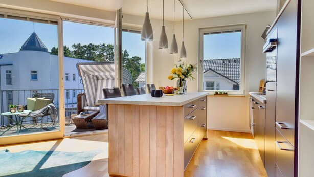 A modern kitchen with a wooden island, large windows, and a view of the city.