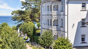 A white building with multiple balconies and a view of the sea.