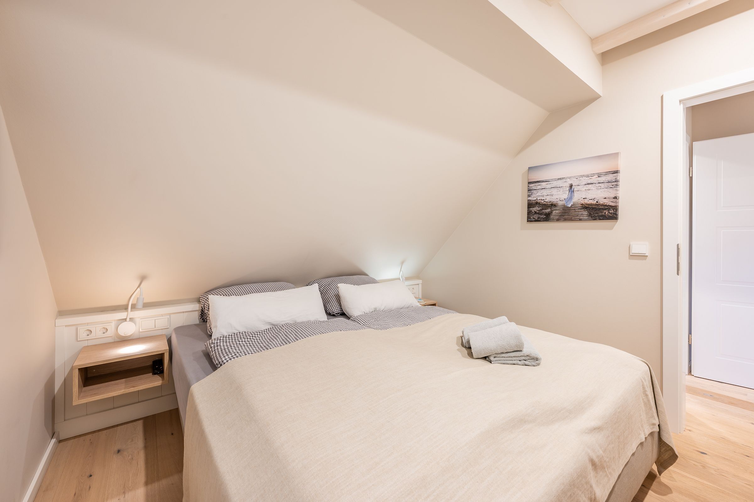 Une chambre bien rangée, avec un lit, une table de chevet et une étagère fixée au mur.
