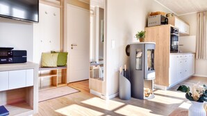 Una cocina moderna con electrodomésticos integrados, una zona de comedor con banco, y un televisor montado en la pared.