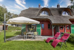 A thatched-roof house with a dining area and outdoor seating. - New, modern, exclusive—that's how the Klein Stresow vacation village describes itself (Klein Stresow)
