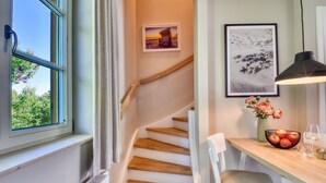 A staircase with wooden steps, a dining area with a table and chairs, and a window with a view of greenery.