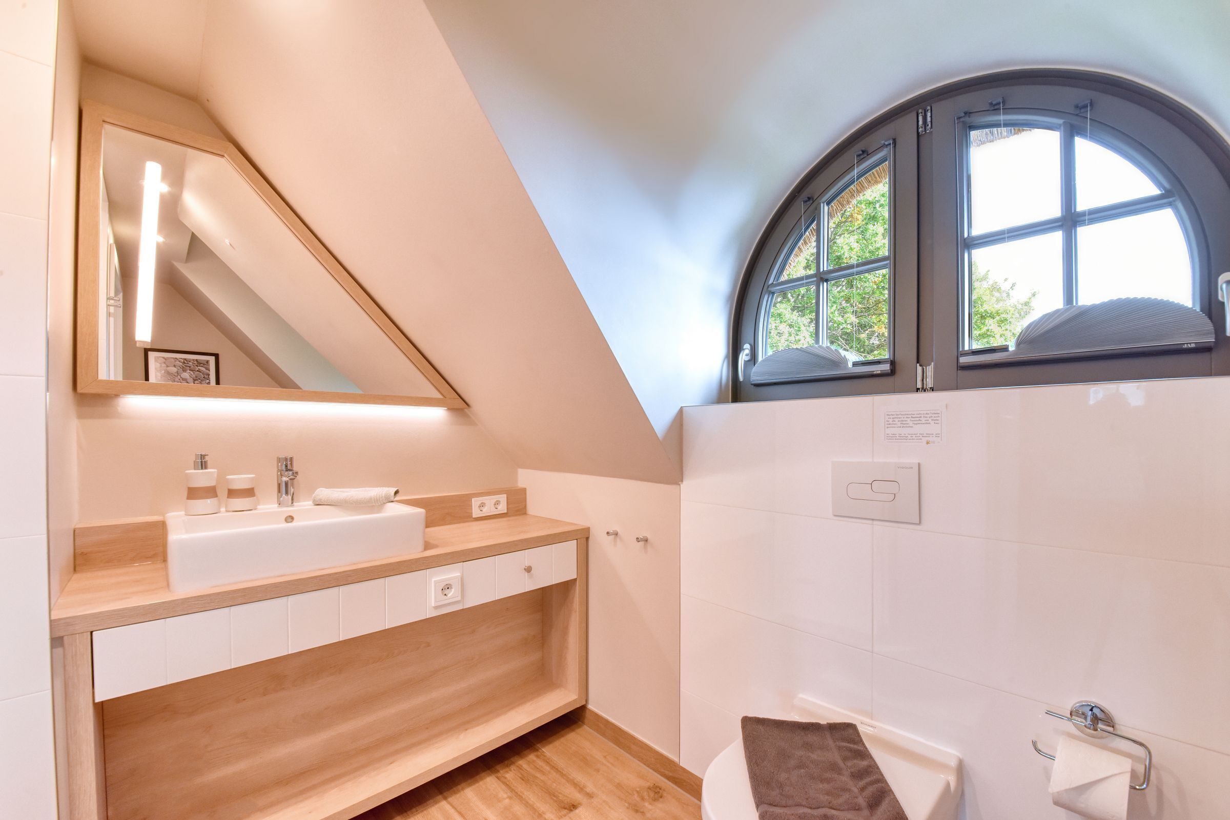 Un baño moderno con tocador de madera, un espejo grande, una bañera y un tragaluz.