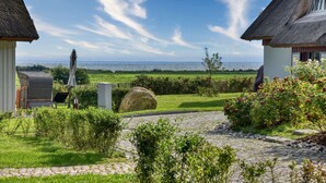 A coastal property with a thatched-roof building, a paved pathway, and a view of the sea. - Newly built, modern, exclusive - that describes the Klein Stresow vacation village (Klein Stresow)