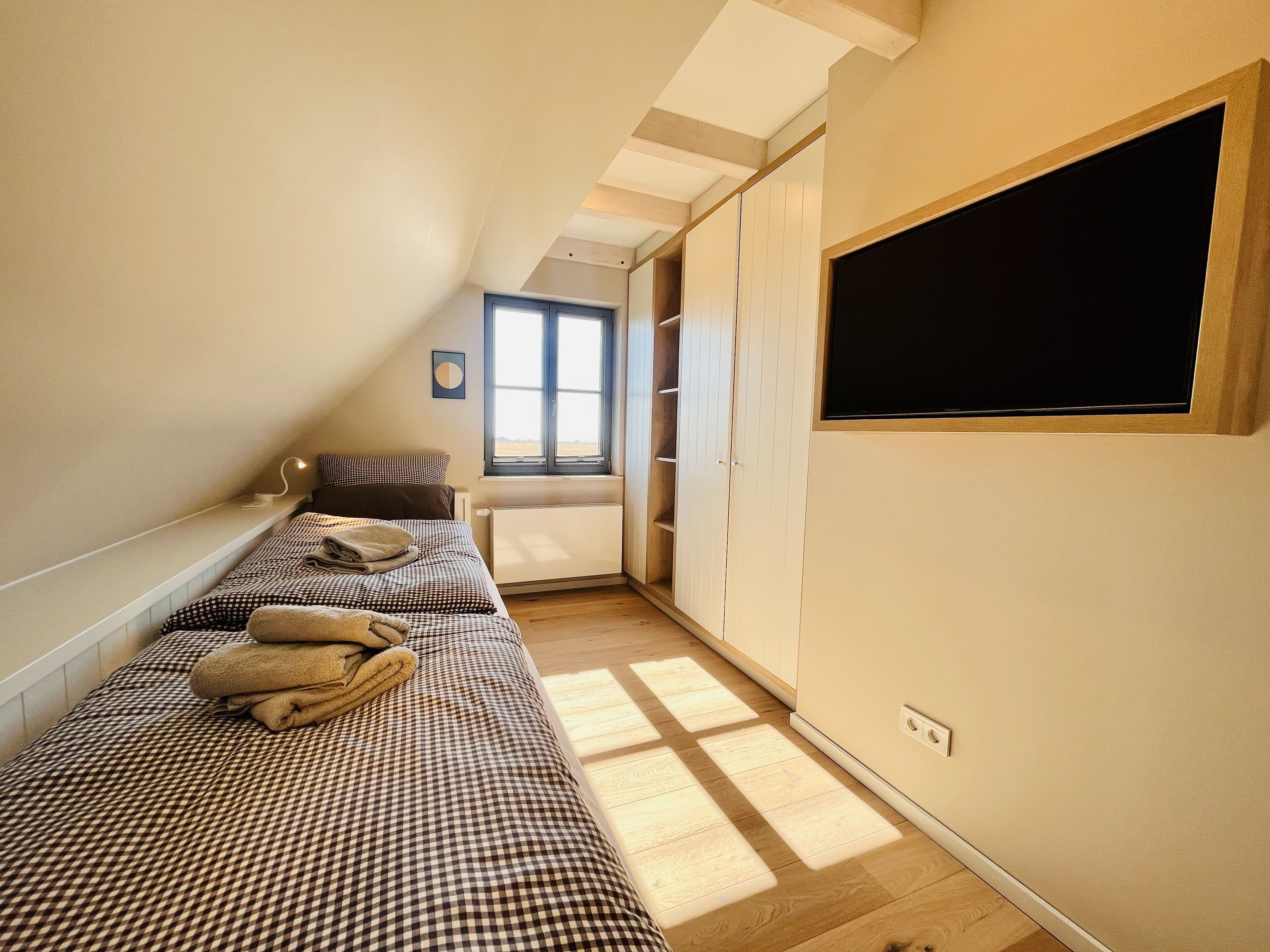 Une chambre avec deux lits simples, une fenêtre, un radiateur et une armoire.