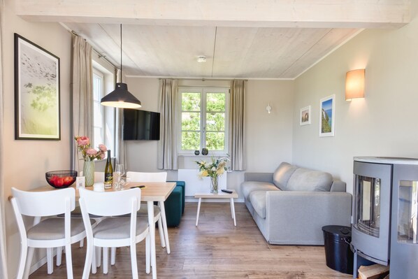 A living room with a dining area, a sofa, a TV, and a fireplace. - Newly built, modern, exclusive - that describes the Klein Stresow vacation village (Klein Stresow)