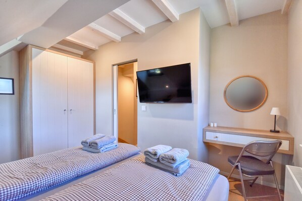 A bedroom with two beds, a desk, a chair, a TV, and a mirror. - Newly built, modern, exclusive - that describes the Klein Stresow vacation village (Klein Stresow)
