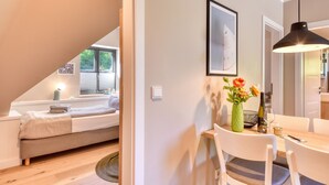 A modern, well-lit room with a bed, a dining table with chairs, a vase with flowers, and a framed picture on the wall. - Newly built, modern, exclusive - that describes the Klein Stresow vacation village (Klein Stresow)