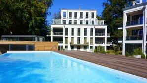 Una piscina con cubierta de madera, rodeada de edificios modernos con balcones y ventanas amplias.