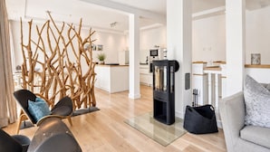 Una sala de estar moderna con chimenea, un comedor y una cocina al fondo.