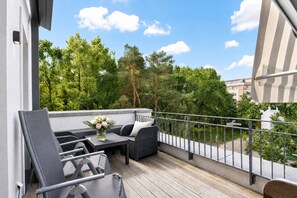 A balcony with outdoor furniture, a table with a vase of flowers, and a view of trees and buildings. - Home port: Your Baltic Sea retreat at Villa Sofie Binz - with roof terrace (Binz)