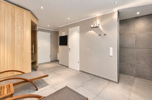 Un vestíbulo de hotel con un mostrador de recepción de madera, un televisor de pantalla plana en la pared y un suelo de baldosas.