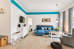 Una sala de estar moderna con un sofá azul, una mesa de centro blanca y un sillón gris.