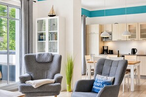 A modern living room with grey armchairs, a bookshelf, and a view of the outdoors.