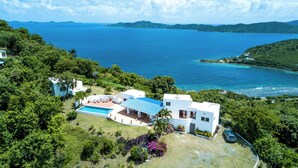 Una casa moderna con piscina, immersa nel verde e affacciata su un'ampia distesa d'acqua.