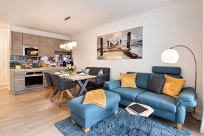Ein modernes Wohnzimmer mit Essbereich, einer Sofagarnitur und einer Küche.