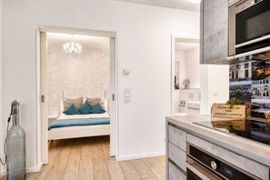 Ein modernes Interieur mit einem Bett in einer Nische, einer Küche mit digitaler Uhr und einer Wand mit Stadtbild-Foto.