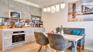 Une cuisine moderne dotée d’un four encastré et d’un coin repas avec une table et des chaises.