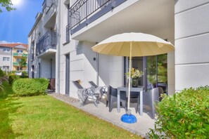 Ein modernes Apartmenthaus mit Balkon, Sitzgelegenheit im Freien und einem großen Sonnenschirm.