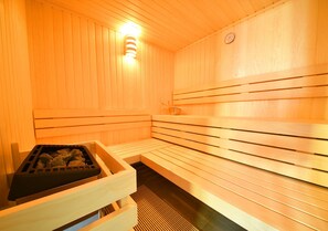 Un sauna avec des murs et des bancs en bois, un radiateur et une horloge au mur.