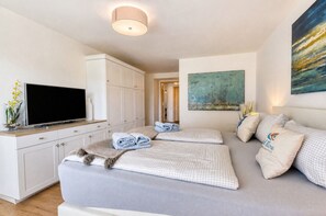 Un dormitorio moderno con un televisor de pantalla plana, sofá cama y un cuadro en la pared.