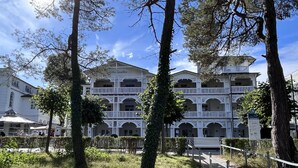 A multi-story building with balconies, surrounded by trees and a pathway. - Strandlust 610, Villa Seeadler:Unique Baltic Sea view & cozy ambience. (Binz)