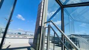Un edificio moderno con fachada de vidrio, barandillas metálicas y una vista despejada del cielo.