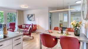 Un comedor moderno con sillas rojas, una mesa de madera y un florero con flores.